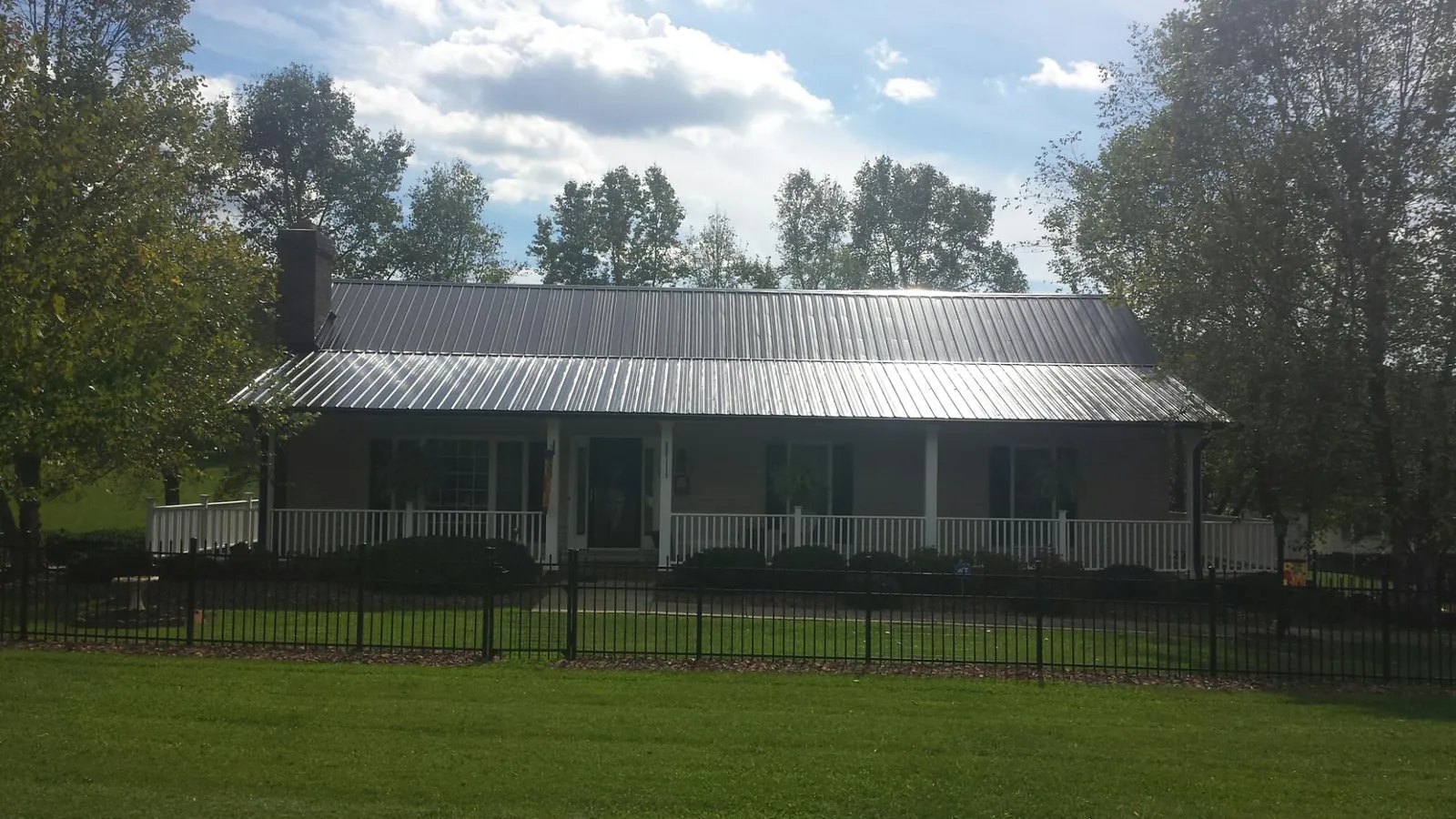 Gray metal roof on a brick ranch with a full width front porch — Gutter Guard Installation work by our crew in Barney