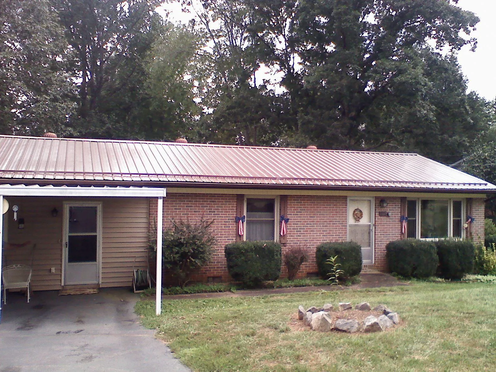 Bronze metal roof and carport on a brick ranch home — Roof Repair work by our crew in Barney