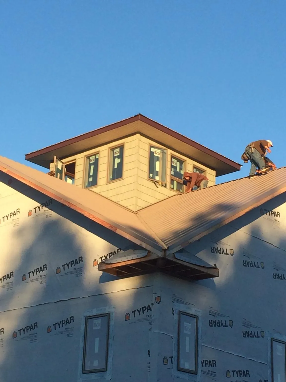 Roofers working around a rooftop cupola on a new metal roof at sunset — Roof Waterproofing in Barney by Roofing Brothers